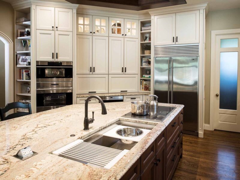 Tulsa kitchen remodel featuring a traditional design with a kitchen island, marble counters, a Galley Workstation, a Wolf induction cooktop, tall pantry storage, Wolf double ovens, a Sub-Zero freezer and refrigerator, and open shelves.