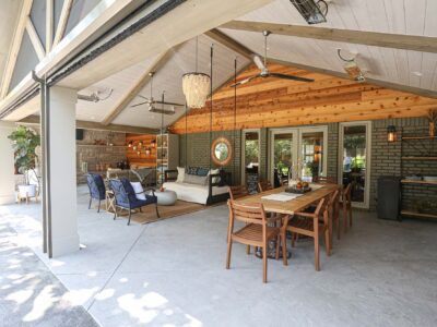 Open patio design and remodel featuring a concrete floor, vaulted ceiling, and distinct dining and living spaces with outdoor furniture. Tulsa kitchen designer and remodeler.