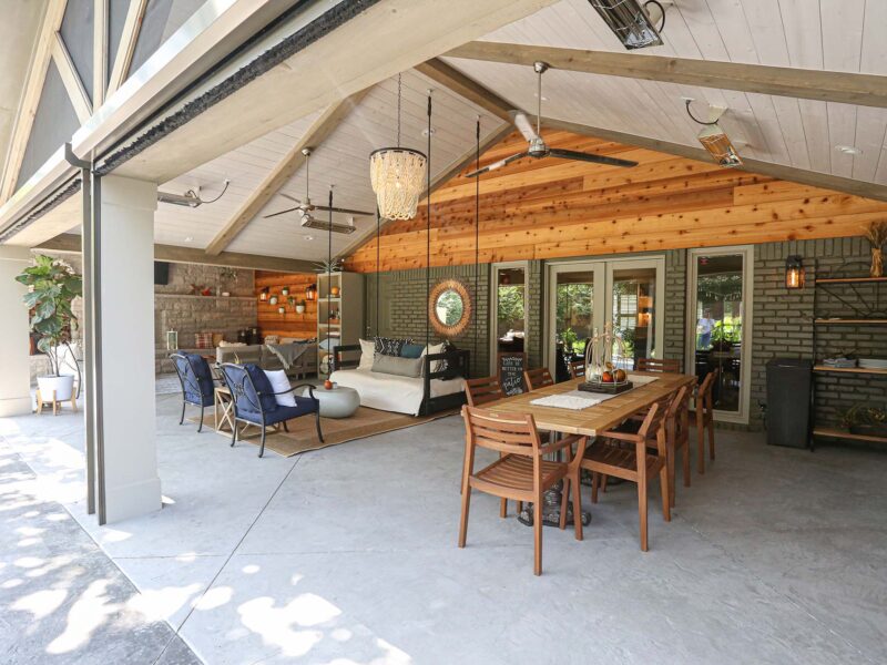 Open-concept Tulsa patio featuring combined dining and living spaces with concrete flooring, vaulted ceiling, and stylish outdoor furniture in design and remodel.