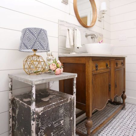 Tulsa powder bathroom design and remodel with vessel sink vanity, rustic cabinetry, shiplap walls, round mirror, wall sconces and weathered table lamp