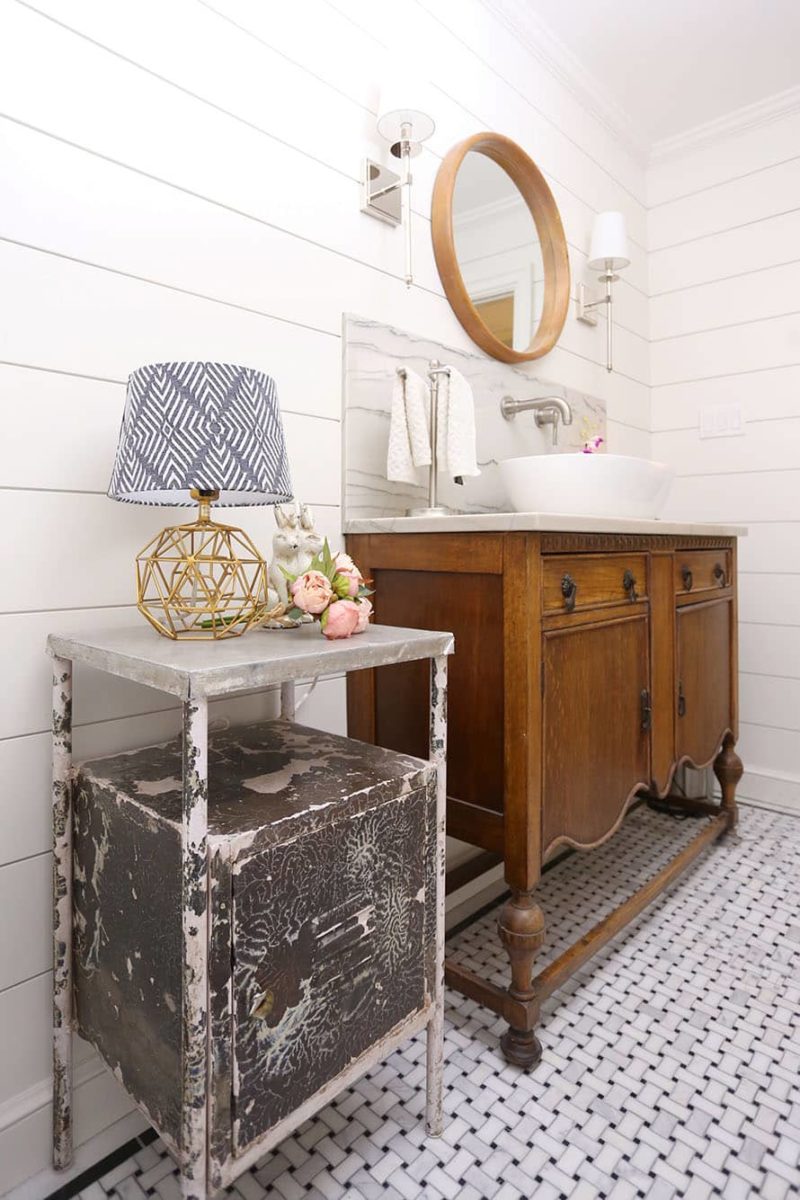 Tulsa powder bathroom design and remodel with vessel sink vanity, rustic cabinetry, shiplap walls, round mirror, wall sconces and weathered table lamp