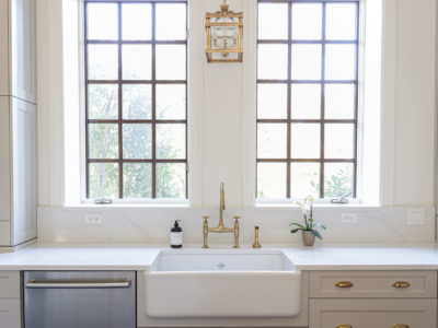 Apron-front white kitchen with decorative wall sconce, wall outlets, quartz counters and white cabinets Tulsa kitchen design