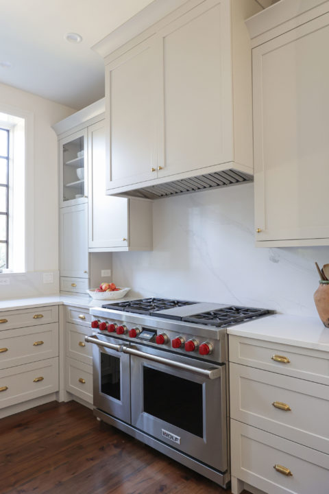 Bright kitchen Wolf range, counter slab backsplash, cabinet vent insert and drawer storage Tulsa kitchen remodel