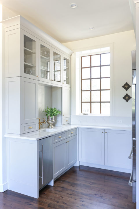 Kitchen beverage space with wood floors, under counter ice maker, bar sink, white cabinets with glass fronts and crown molding Tulsa kitchen remodel
