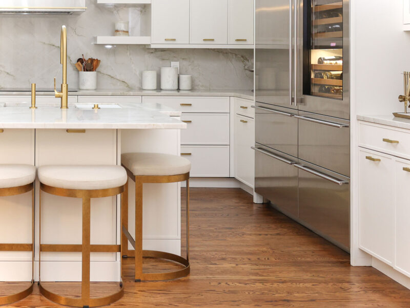 Tulsa kitchen remodel featuring an island with seating, a Sub-Zero and Wolf refrigerator and wine storage, and surrounding white cabinet storage.