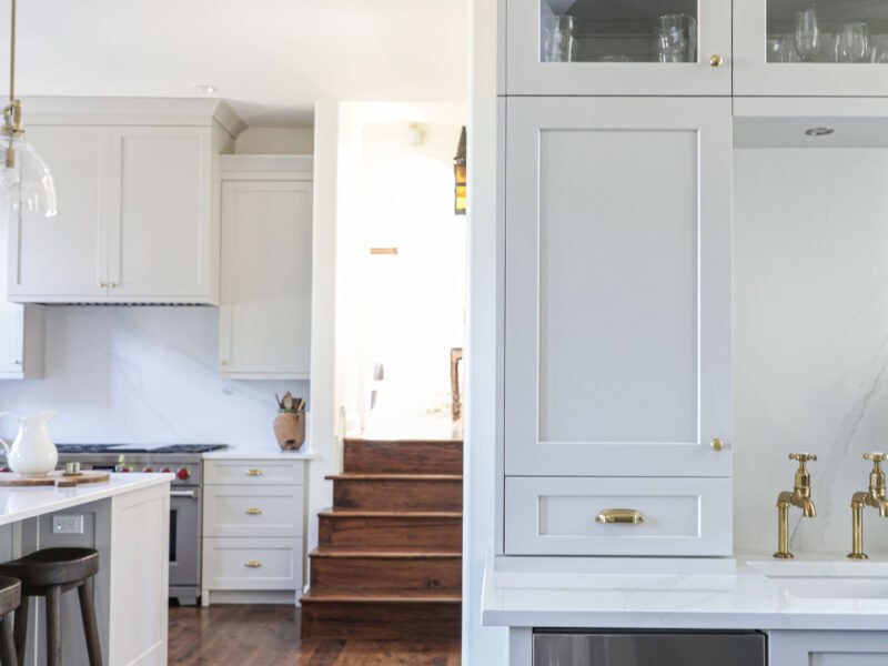 Tulsa kitchen design and remodel featuring an open beverage space with wood floors, an under counter ice maker, a bar sink, and white cabinets with glass fronts.
