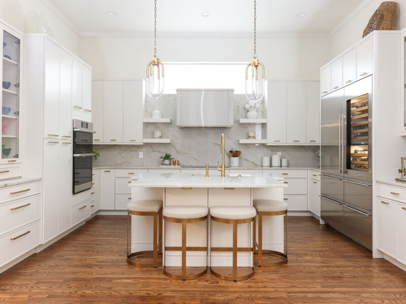 Tulsa kitchen remodel featuring an open white kitchen with a large island with seating, decorative pendant lights, and high-end Dacor, Sub-Zero, and Wolf appliances.