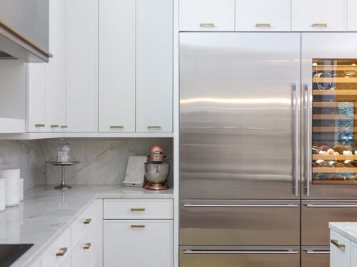 Tulsa kitchen remodel featuring a Sub-Zero refrigerator and wine storage, white base and wall cabinets, and wood flooring.