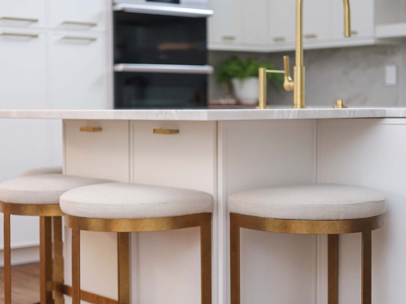 Tulsa kitchen remodel featuring a large kitchen island with under-counter storage, seating, a Galley Workstation, and a modern Galley Tap faucet. The space includes white counters and matching white cabinet storage.