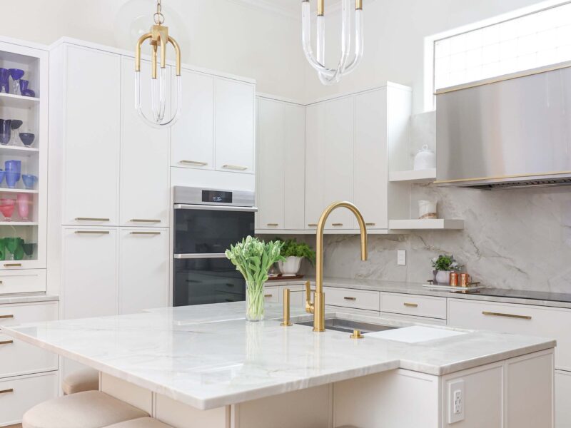 Tulsa kitchen remodel featuring a white kitchen island with seating and pendants. The space includes Dacor ovens, a tall pantry storage unit, a stainless steel vent hood, and an induction cooktop.