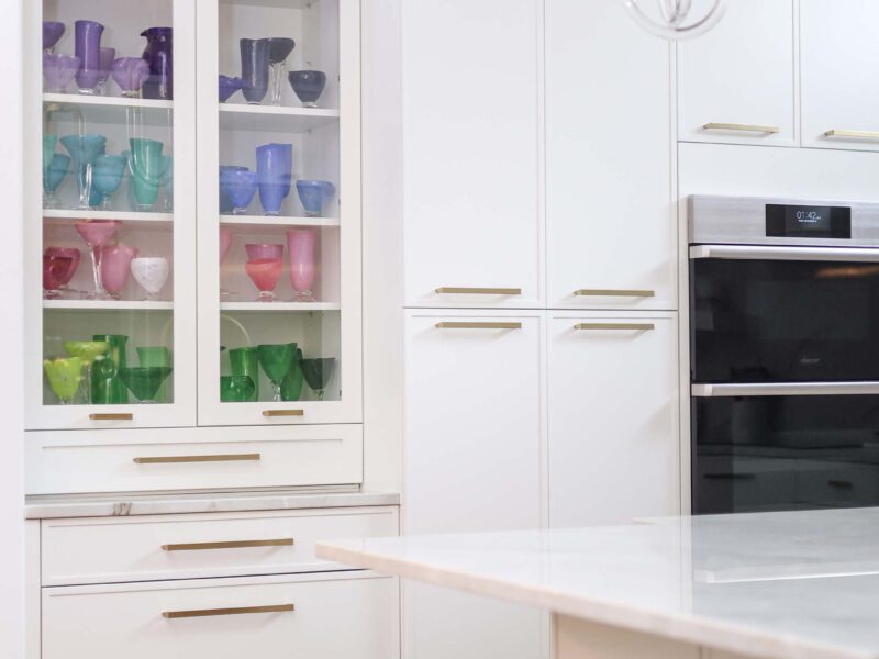 Tulsa kitchen remodel featuring a tall white pantry storage unit with glass-front doors, built-in Dacor ovens, and a kitchen island with seating.