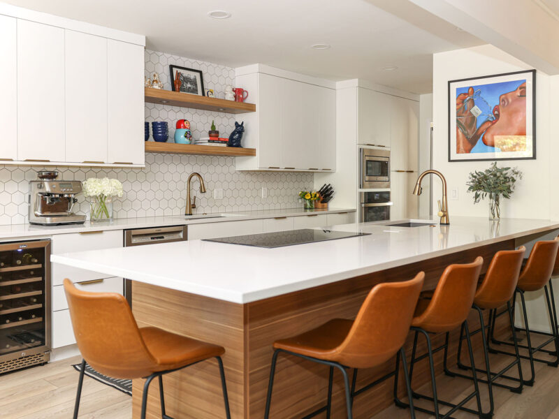 Tulsa kitchen remodel featuring white flat-panel cabinets, a peninsula with seating, an induction cooktop, a bar sink, and decorative floating shelves.