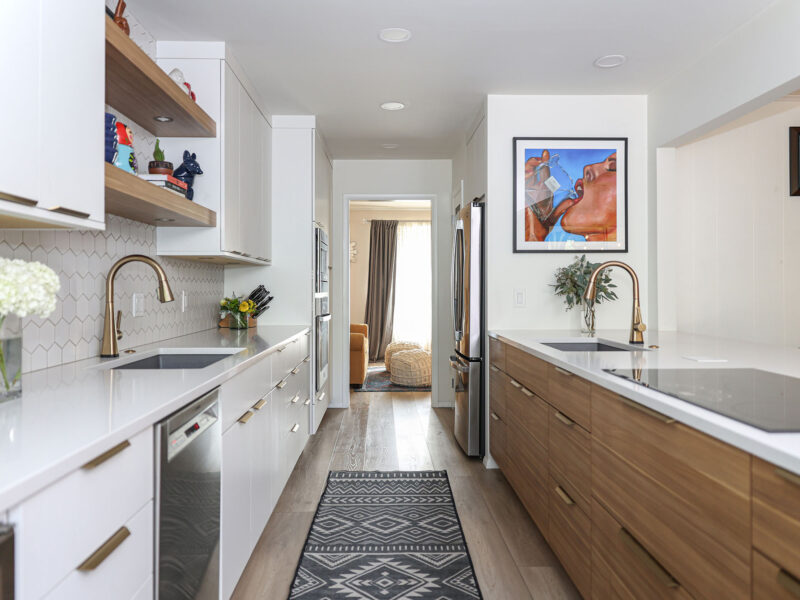 Tulsa kitchen remodel featuring white laminate cabinets, drawer storage, an under mount sink, floating shelves, a bar sink, white counters, an induction cooktop, and luxury vinyl wood flooring.