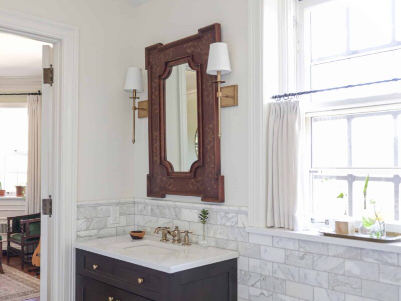 A charming Tulsa bathroom design and remodel featuring a single-sink vanity, wainscoting with a subway tile backsplash, and a rustic pendant light.