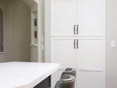 Recessed tall kitchen pantry white cabinet storage, television above, island seating Tulsa kitchen design and remodel