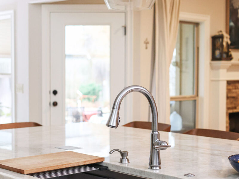 Tulsa kitchen design and remodel featuring a Galley Workstation sink, quartz countertops, white cabinet storage, and a pendant light fixture.
