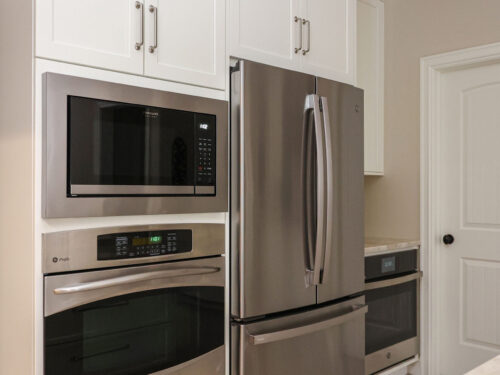 Tulsa kitchen remodel featuring built-in microwave and oven, a french door refrigerator, and an undercounter base oven. The design also includes white cabinets and quartz counters.