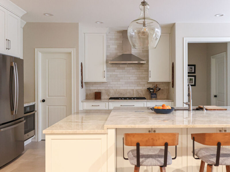 Tulsa kitchen remodel featuring an island with seating, pendant lights, a french door refrigerator, a gas cooktop, a vent hood, and quartz counters.
