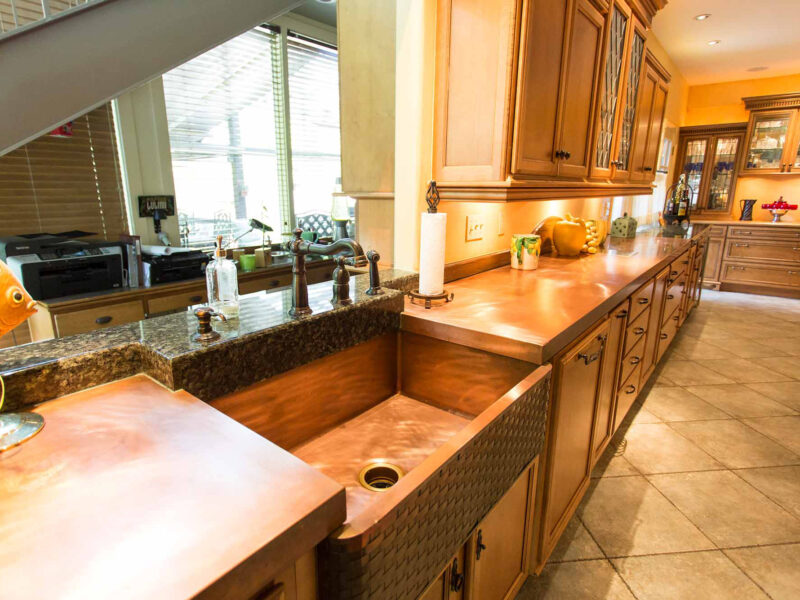 Tulsa kitchen design and remodel featuring a copper apron front kitchen sink, countertop, and wood-stain base cabinet storage.