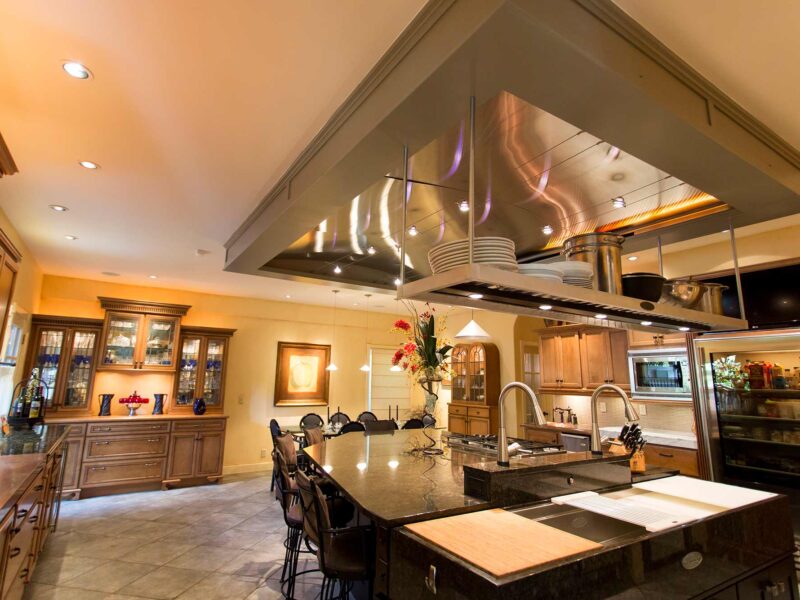 Tulsa kitchen remodel featuring an open classic Tuscan kitchen with a large island, a decorative vent hood, granite counters, a copper counter, a Galley Workstation, a butler's pantry, tile flooring, and stainless steel appliances.