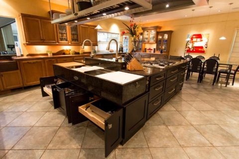 Tulsa kitchen remodel and design featuring a Tuscan-style kitchen with an island, a Galley Workstation, an island vent hood, and dark cabinet drawer storage.