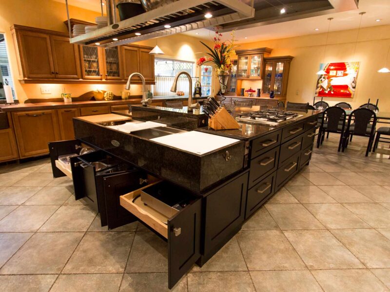 Tulsa kitchen remodel and design featuring a Tuscan-style kitchen with an island, a Galley Workstation, an island vent hood, and dark cabinet drawer storage.
