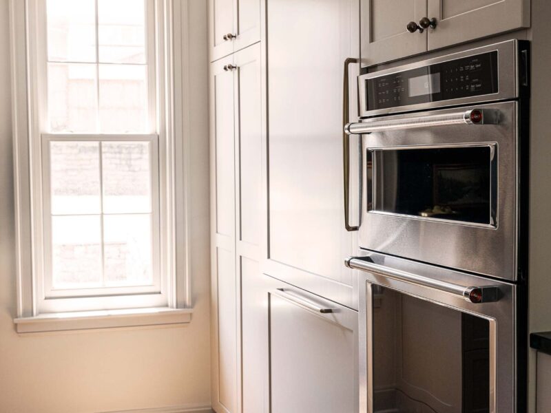Tulsa kitchen design and remodel featuring a tall pantry storage unit, built-in double ovens, and a panel-front refrigerator, all with crown molding at the ceiling.