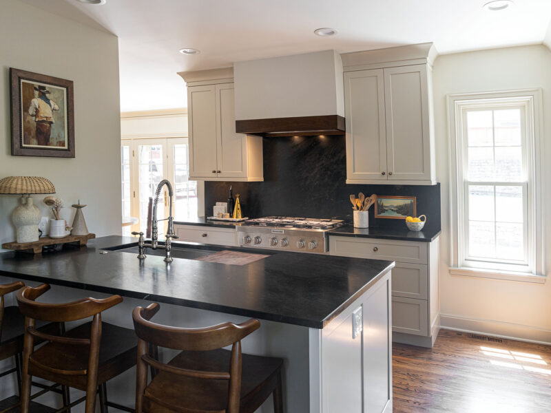 Tulsa kitchen design and remodel featuring a peninsula with a Galley Workstation and a range top. The design includes black cabinet storage.