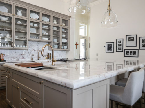Tulsa kitchen remodeler showcasing a large kitchen island with a Galley Workstation, an apron-front sink, an ogee-edge countertop, a matching backsplash, and surrounding cabinet storage.