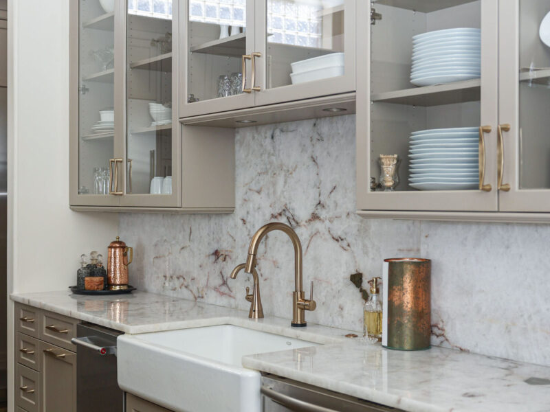 Tulsa kitchen design and remodel featuring an apron-front sink, a stainless steel dishwasher, and an ice maker. The kitchen includes cabinet storage, a countertop, and a backsplash.
