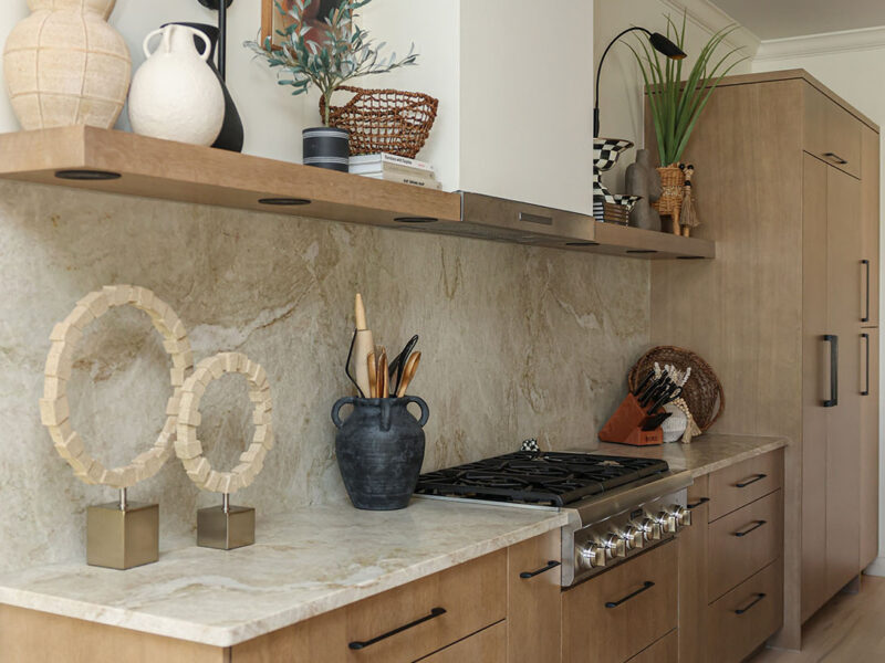 Tulsa kitchen remodel featuring a gas rangetop, custom vent hood, and a panel-front freezer and refrigerator. The design includes thick counters and a floating shelf.