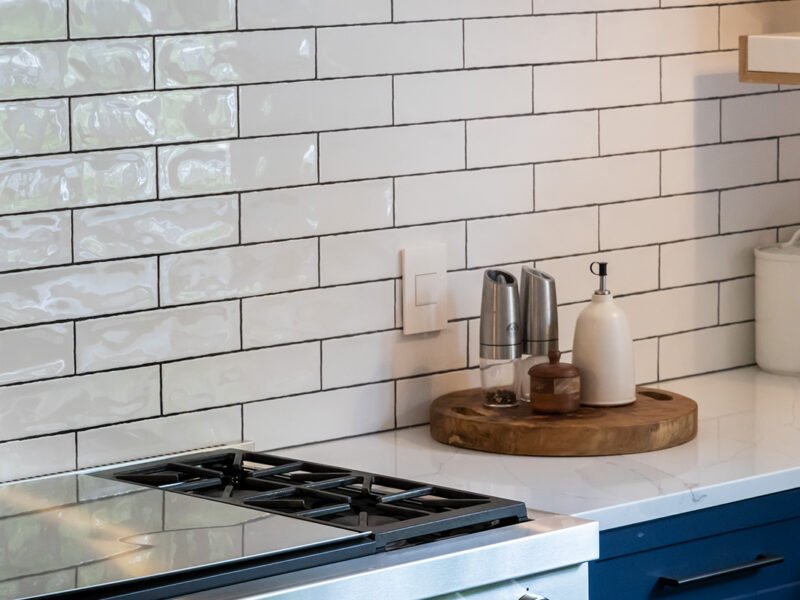 Tulsa kitchen remodel featuring a gas range, white subway tile backsplash, blue cabinets, and white counters.