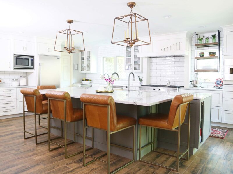 Tulsa kitchen design and remodel featuring white shaker perimeter cabinets, slate shaker island cabinet storage with seating, white counters, wood floors, stainless GE appliances, and a hearth pizza oven.