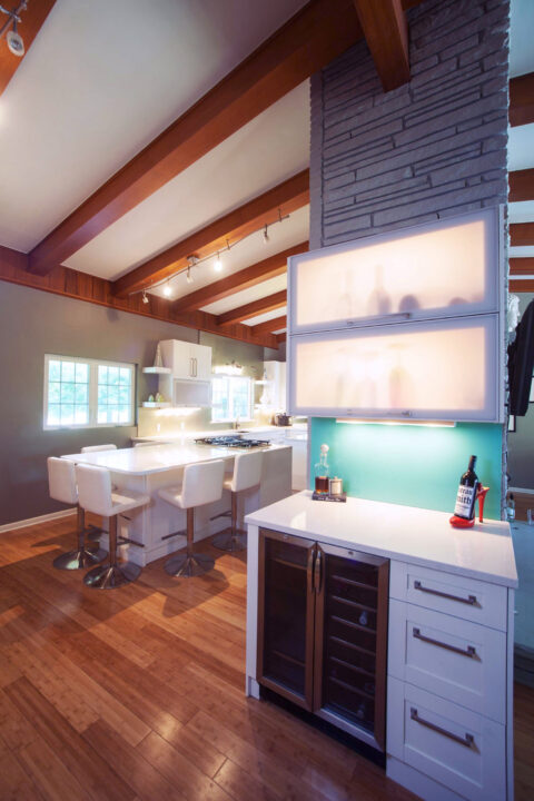 Tulsa kitchen remodel featuring a beverage bar with frosted glass wall cabinets, a built-in wine and beverage refrigerator, and a vaulted ceiling with a stone accent wall.
