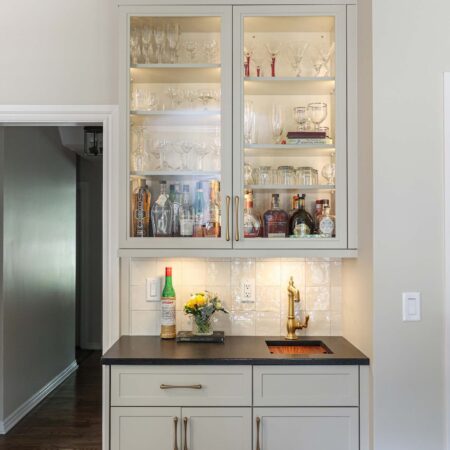 Custom bar space with cabinet lighting and black counters. A tile backsplash completes the modern look. Tulsa kitchen design and remodel.