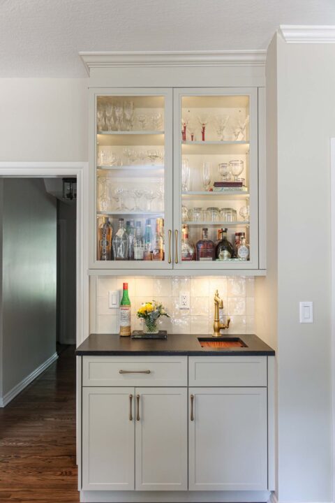 Custom bar space with cabinet lighting and black counters. A tile backsplash completes the modern look. Tulsa kitchen design and remodel.