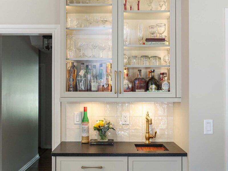 Custom bar space with cabinet lighting and black counters. A tile backsplash completes the modern look. Tulsa kitchen design and remodel.