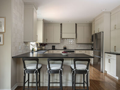 Greige kitchen remodel featuring a large peninsula with seating, black counters, and GE appliances. Tulsa kitchen design and remodel.