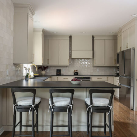Greige kitchen remodel featuring a large peninsula with seating, black counters, and GE appliances. Tulsa kitchen design and remodel.