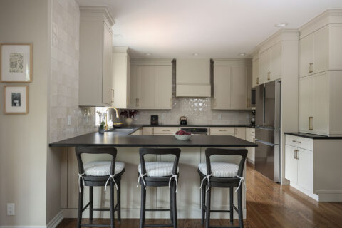 Greige kitchen remodel featuring a large peninsula with seating, black counters, and GE appliances. Tulsa kitchen design and remodel.