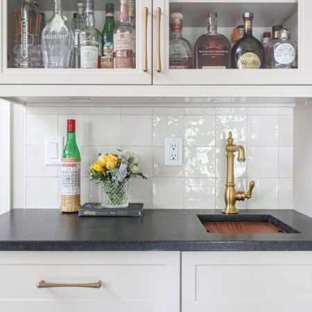 Custom kitchen bar with a sink and black counters. A tile backsplash completes the design. Tulsa kitchen design and remodel.