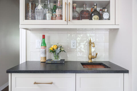 Custom kitchen bar with a sink and black counters. A tile backsplash completes the design. Tulsa kitchen design and remodel.