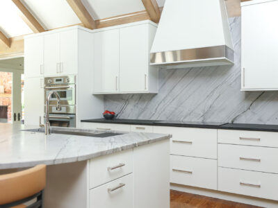 Modern white maple kitchen featuring a cooktop, vent hood, and built-in ovens. Tulsa kitchen designer.