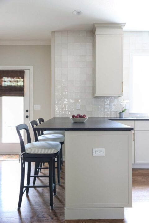 Kitchen peninsula with seating, bright cabinets, and a tile backsplash.