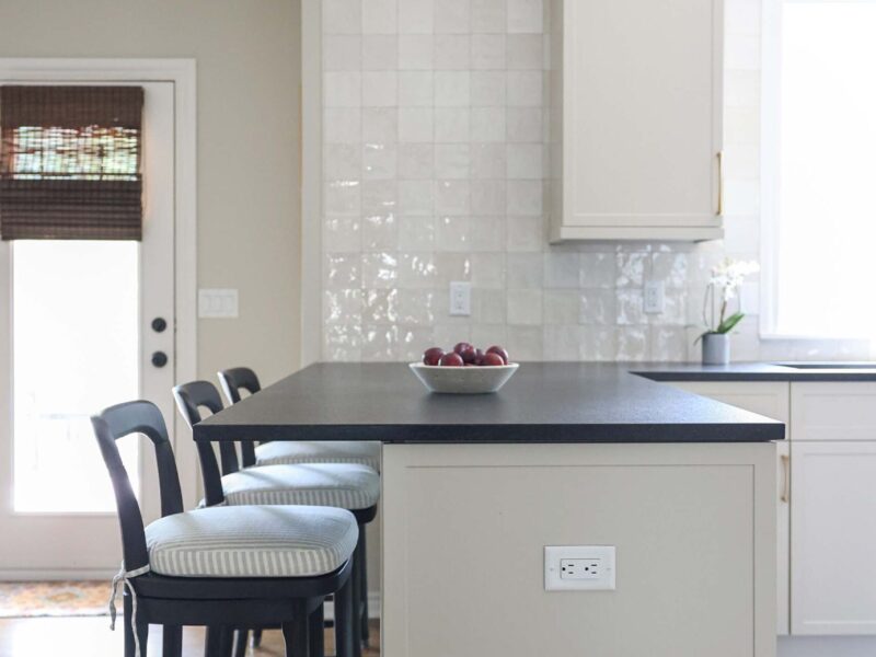 Kitchen peninsula with seating, bright cabinets, and a tile backsplash.