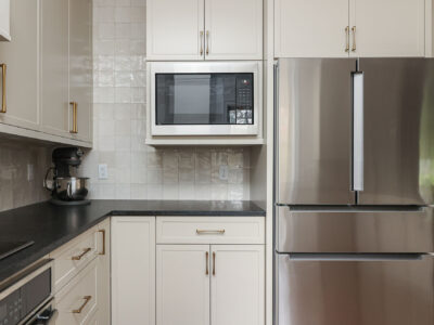Bright kitchen design with a microwave and a French door refrigerator. Features include a tile backsplash and bright cabinetry. Tulsa kitchen design and remodel.