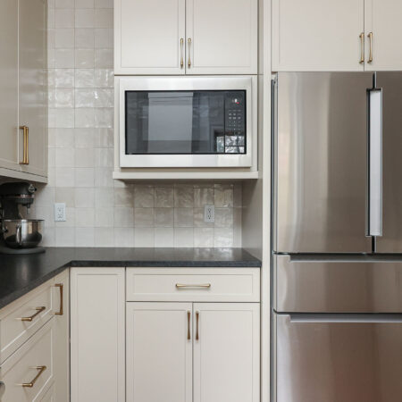 Bright kitchen design with a microwave and a French door refrigerator. Features include a tile backsplash and bright cabinetry. Tulsa kitchen design and remodel.