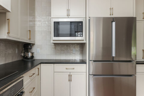 Bright kitchen design with a microwave and a French door refrigerator. Features include a tile backsplash and bright cabinetry. Tulsa kitchen design and remodel.