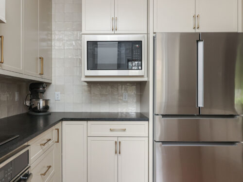 Bright kitchen design with a microwave and a French door refrigerator. Features include a tile backsplash and bright cabinetry. Tulsa kitchen design and remodel.