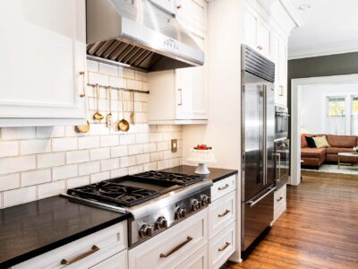 Tulsa kitchen design and remodel featuring a Thermador professional gas rangetop, a vent hood, a subway tile backsplash, a stainless steel Sub-Zero refrigerator and freezer, and Wolf and Gaggenau ovens.